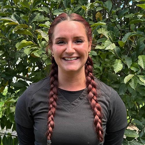 Robin with her hair braided outside in front of a bush